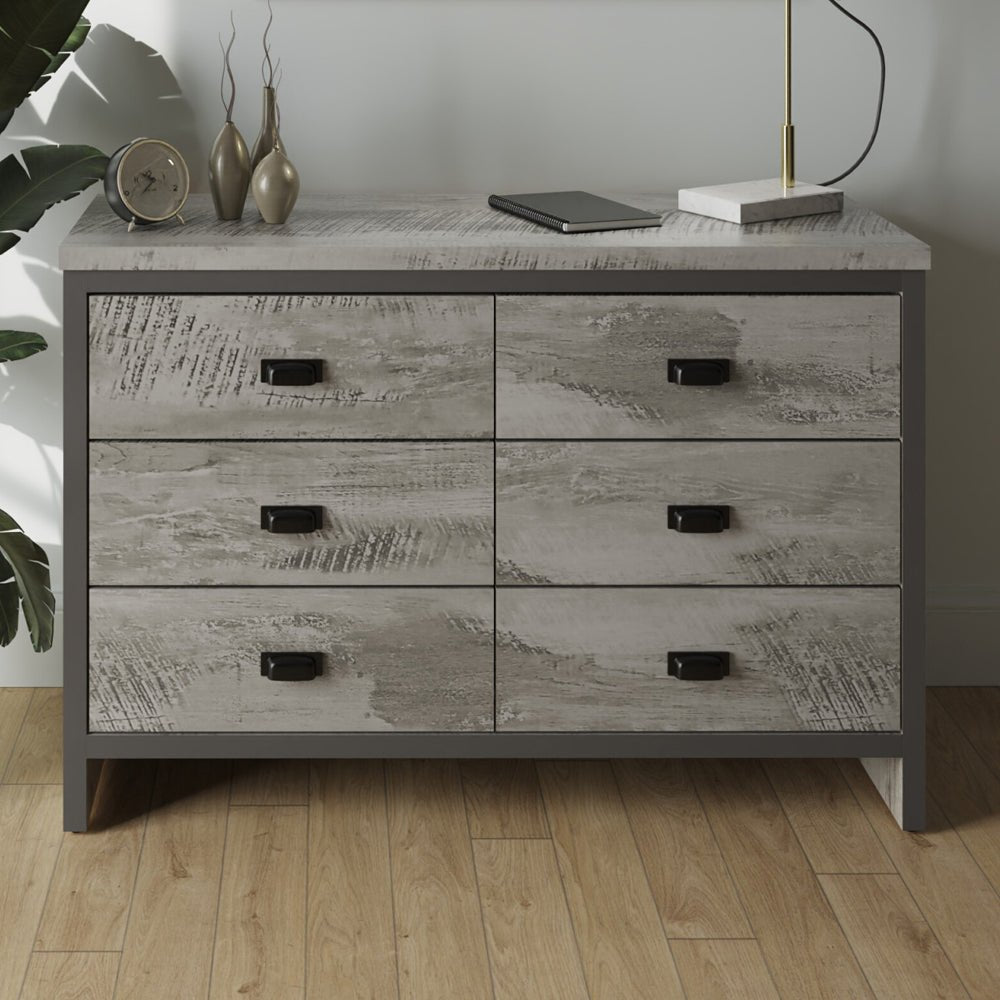 Grey Balcombe 6-drawer chest with weathered wood effect, black handles, and dark frame. Styled with decor.