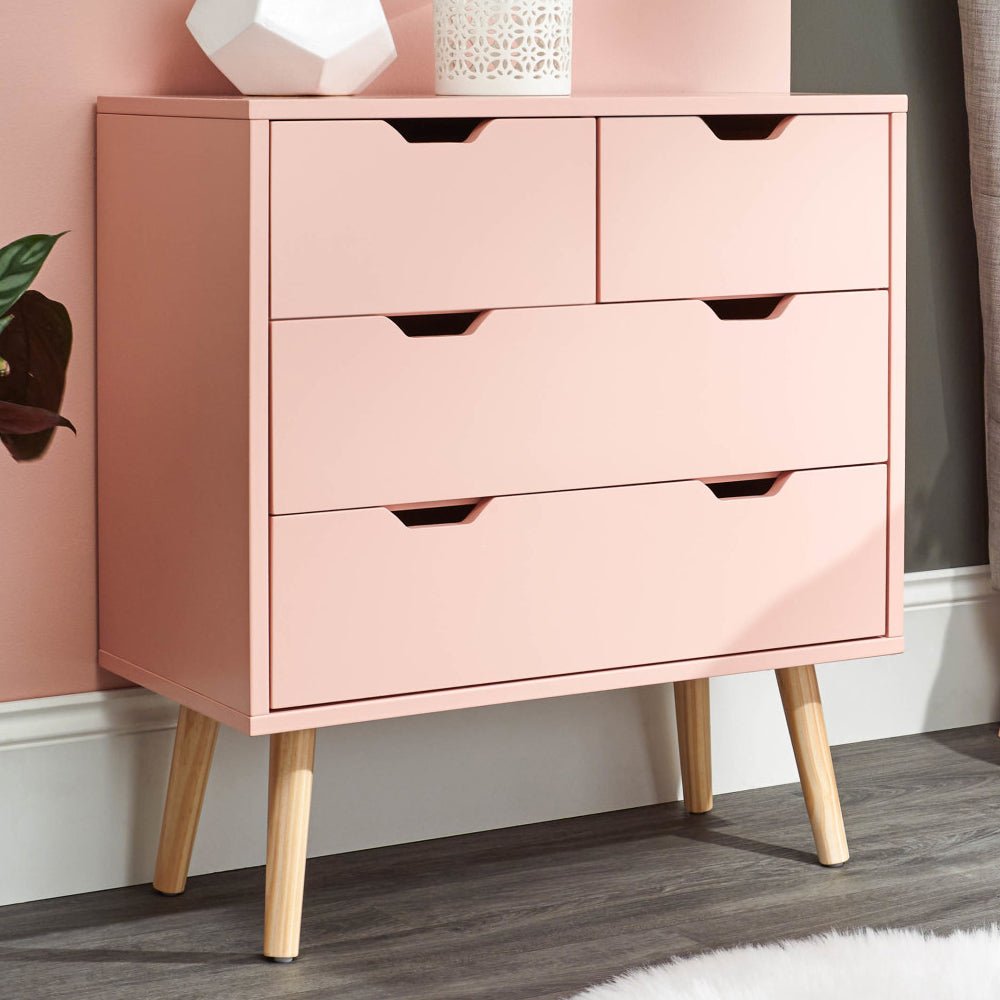 Coral pink wooden chest of 4 drawers with angled legs and cutout handles.