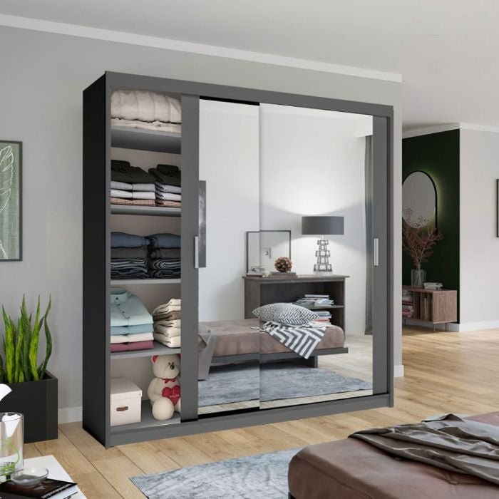 A modern bedroom features the CHOICEWARDROBE CHICAGO II 2 Door Sliding Door Wardrobe (203 cm) with grey mirrored doors. One door is open, displaying neatly folded clothes, boxes, and a teddy bear inside; wood flooring and contemporary decor complete the look.