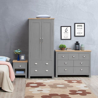 The bedroom showcases the CHOICEWARDROBE Lisbon Grey 3 Piece Set—wardrobe, chest of drawers, and bedside table. Decor includes framed prints, a clock, plants, lantern, and a floral rug beside the beige bed.