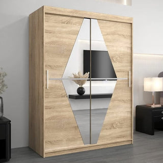 The CHOICEWARDROBE Beloit Sliding Door Wardrobe features two 150cm Sonoma Oak mirrored doors with central diamond-shaped mirrors, standing against a wall beside a lamp, black nightstand, and mounted TV.