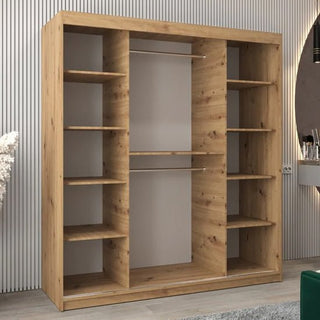 The Beloit Mirrored Wardrobe with 2 sliding doors in artisan oak (180cm) stands against a striped wall in a modern room, offering spacious storage with multiple shelves and hanging rods behind its sleek facade.