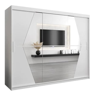 The Beloit Mirrored Wardrobe 3 Sliding Doors 250cm in White features sleek mirrored panels and angular designs, reflecting a modern interior with a wall-mounted TV, floating shelf, glassware, and a vase with dried plants.