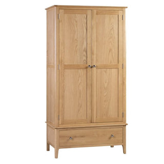 The Callia Wooden Wardrobe With 2 Doors 1 Drawer In Natural features a solid oak build, paneled doors, metal knobs, and a roomy bottom drawer. Its light natural finish and four short legs offer elegant, practical storage for your bedroom.