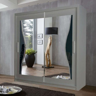 The CHOICEWARDROBE 203cm Sliding Door Mirrored Wardrobe in matt grey with wave-design panels reflects a floor lamp, potted plant, framed pictures, and a wooden sculpture in a contemporary space with grey walls.
