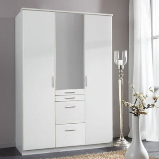 The CHOICEWARDROBE Acorn 3 Door Mirrored Wardrobe in a 135cm white finish features mirrors, drawers, shelves, and a hanging rail, perfect for modern rooms with lamps, curtains, and floral decor.