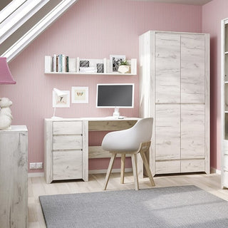 A modern workspace with a white desk, monitor, chair, bookshelf, and a CHOICEWARDROBE Alink Wooden Wardrobe—2 doors, 2 drawers—in white. Set against a pink-striped wall with sloped ceiling window, wooden floor, and gray rug.