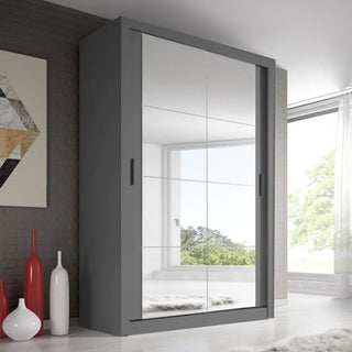 The CHOICEWARDROBE Aliso 2 Door Mirrored Sliding Wardrobe in matt grey stands against the wall, its full-length mirrors reflecting a window, trees, and the room. Three decorative red and white vases are placed nearby.