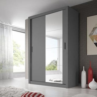 The CHOICEWARDROBE Allen 2 Door Sliding Wardrobe – 150cm Matt Grey with Mirror offers space-saving, modern bedroom storage and stands stylishly in a bright room with white walls, decorative vases, geometric wall art, and sheer-curtained windows.