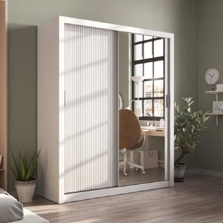 The CHOICEWARDROBE Altoona Mirrored Sliding Door Wardrobe (180cm, white, ribbed modern design) stands by a green wall; its mirrored door reflects a home office with a brown chair, desk, window, and a nearby plant on the floor.