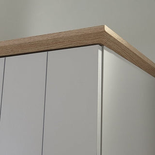 Close-up of the CHOICEWARDROBE Alverton 3 Door Wardrobe in grey, featuring an oak effect top with vertical grooves and a light wood trim, set against a plain light-colored wall.