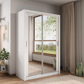 The CHOICEWARDROBE Ames 2 Door Mirrored Sliding Wardrobe (150cm, Matt White Finish) stands in a corner with wooden floors, beige curtains, a potted plant, and a window displaying green trees.