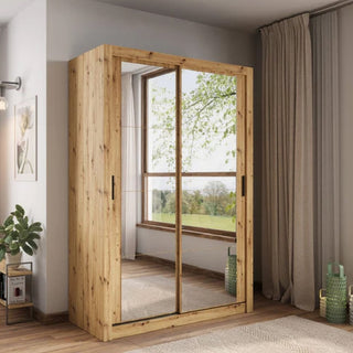 The CHOICEWARDROBE Ames 2 Door Mirrored Sliding Wardrobe in rustic oak stands by a window with beige curtains. In the corner, an oak artisan-style wardrobe is accented with a potted plant, painting, and decor.