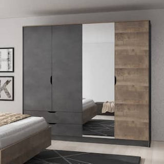 The CHOICEWARDROBE Arvada 220cm 4 Door Sliding Wardrobe in Grande Matera Oak & Mirror stands against a light wall, reflecting the bed and rug; it features drawers, shelves, and a hanging rail for modern storage.
