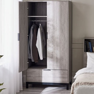 The CHOICEWARDROBE Baara 2 Door Wardrobe (92 cm, Light Grey Ash Effect) with black metal legs and drawer offers modern industrial storage. Two doors open to reveal shirts on a metal rod; a lower drawer is closed beside a softly lit bed.