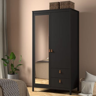 The CHOICEWARDROBE Barcila Mirrored Wooden Wardrobe, featuring 2 doors, 2 drawers, a full-length mirror, and leather-style handles in black, stands out in the corner with woven baskets on top, next to a potted plant, beige chair, and curtains.