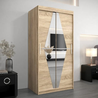 The CHOICEWARDROBE Beloit 100cm Mirrored Sliding Door Wardrobe in Sonoma Oak Finish, featuring shelves, hanging rails, and drawers, is shown in a modern room with a black nightstand, lamp, and a vase of dried flowers.