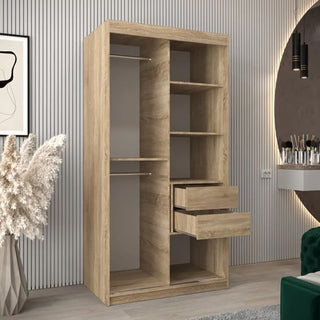The CHOICEWARDROBE Beloit 100cm Mirrored Sliding Door Wardrobe in Sonoma Oak finish features a modern design with shelves, hanging rails, and integrated drawers; it stands stylishly against neutral decor and vertical wall paneling.