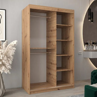 The CHOICEWARDROBE Beloit 120cm Artisan Oak Mirrored Wardrobe features two sliding doors—with a diamond-cut mirror—two hanging rods on the left, and four storage shelves on the right, standing stylishly amid vertical wall panels and décor.