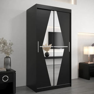 The CHOICEWARDROBE Beloit 2 Door Mirrored Sliding Wardrobe in a 100cm black finish features geometric mirrored doors and smooth glide, adding space-saving style to a modern room with a vase of flowers, lamp, and wall-mounted TV.