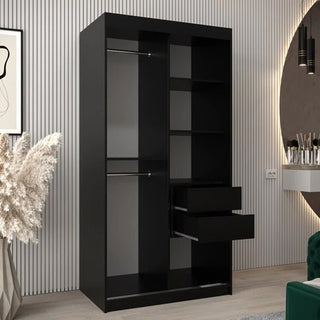 The CHOICEWARDROBE Beloit 2 Door Mirrored Sliding Wardrobe in a black finish with geometric mirror and smooth-glide doors stands in a modern room with light wood floors, striped walls, pampas grass, and a vanity.