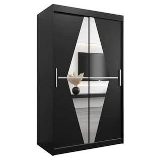 The CHOICEWARDROBE Beloit 2 Door Sliding Mirrored Wardrobe in 120cm matte black features a modern geometric mirror design, hanging rail, and shelves—reflecting décor like a vase with dried plants and a wall-mounted TV for stylish bedroom storage.