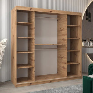 The CHOICEWARDROBE Beloit 200cm Mirrored Sliding Door Wardrobe in Artisan Oak, featuring a modern geometric mirror design and premium storage, stands against a light vertically-grooved wall beside modern decor and a green chair.