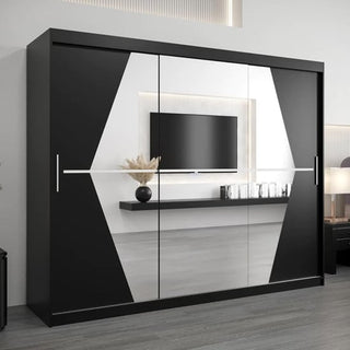 The CHOICEWARDROBE Beloit 3 Door Sliding Mirrored Wardrobe (250 cm, Black with Geometric White Panels) features long silver handles, modern design, shelves, and hanging rails. Its mirrored panels reflect a TV, shelf, and decorative items.
