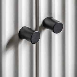 Close-up of two black cylindrical handles on a metallic surface with vertical ridges, as featured on the CHOICEWARDROBE Bienne White Fluted Wooden Wardrobe | 2 Door Wardrobe with Drawers & Black Metal Legs.
