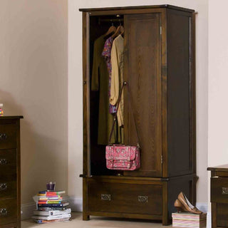 The CHOICEWARDROBE Birtley 90cm 2 Door Wooden Wardrobe in dark brown finish with drawer shows open doors revealing hanging clothes and a pink floral bag, with books, shoes, and storage items placed nearby.