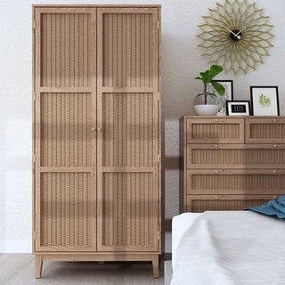 The CHOICEWARDROBE Burdon 85cm Rattan-Front Wooden Wardrobe in rustic oak with woven panels stands beside a dresser, providing ample bedroom storage, while decorative items and art enhance the cozy, boho-style space.