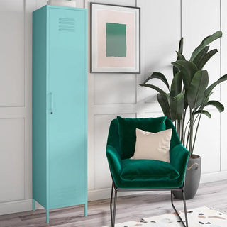 A CHOICEWARDROBE Caches Metal Locker Wardrobe in spearmint stands beside a green velvet chair with white cushion. Above, on the white paneled wall, are a potted plant and framed abstract print, over a patterned rug.
