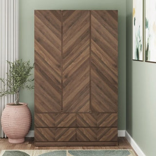 The CHOICEWARDROBE Calder 3 Door Wardrobe in royal walnut chevron finish stands against a green wall, with three doors above six drawers, framed art to the right, a plant on the left, plus a curtain and rug nearby.
