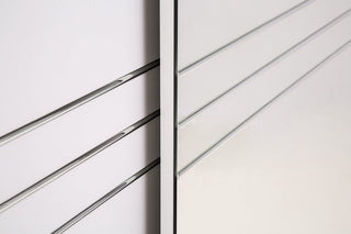 Close-up of two light gray panels with horizontal metallic lines at a right angle, evoking the geometric and minimalistic look of the CHOICEWARDROBE Capri White Sliding 2 Door Wardrobe (203cm), featuring a matt finish, mirror, and storage shelves.