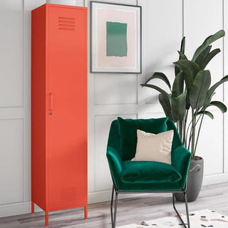 A modern interior with the CHOICEWARDROBE Cerritos 38cm 1 Door Metal Locker Wardrobe in industrial orange, a green velvet armchair with a beige pillow, a potted plant, and an abstract print on a white paneled wall.