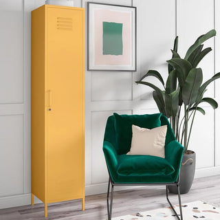 The CHOICEWARDROBE Cerritos 38cm Metal Single Door Wardrobe in yellow stands by a green armchair with a white pillow, near a leafy plant and abstract art on a white-paneled wall in this modern, minimalistic room.