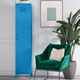 The CHOICEWARDROBE Cerritos 38cm Bold Blue Metal Wardrobe stands beside a green velvet armchair with a beige pillow, set in front of a white paneled wall decorated with leafy plants and abstract art.