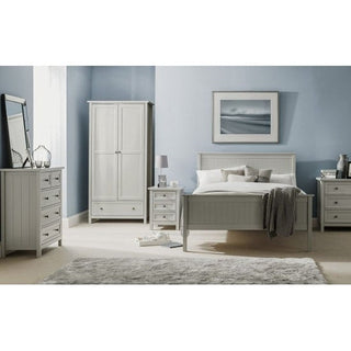 A bedroom with light blue walls, a large bed with white and gray bedding, two nightstands, a dresser with mirror, a CHOICEWARDROBE Cheshire 2 Door Grey Wardrobe with drawer storage and hanging rail, lamp, decor accents, and a gray rug on light carpet.