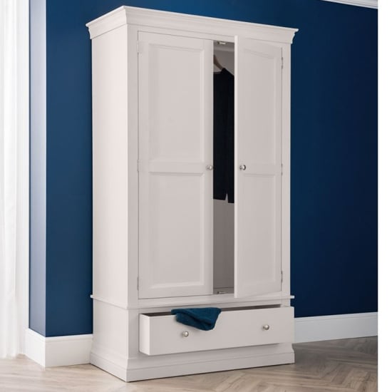 Light grey Chirk 2-door wardrobe with one drawer, partially open, against a blue wall.