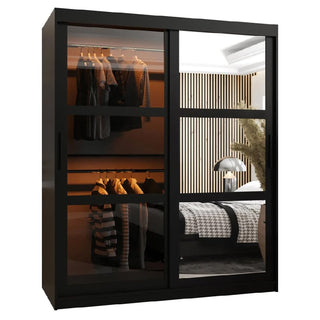 The CHOICEWARDROBE Danville 150cm Black Glass Mirrored Sliding Door Wardrobe features luxury panel design, hanging rails, and shelving, reflecting a modern bedroom with a bed, lamp, wood slats, and plant for a sleek contemporary style.
