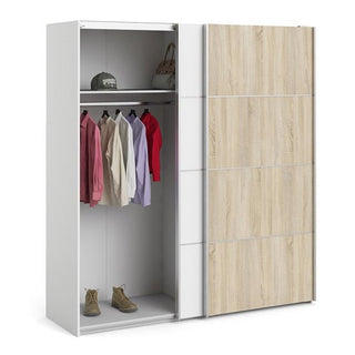 The CHOICEWARDROBE Dcap 180cm Oak & White Sliding Door Wardrobe showcases shirts on hangers, a cap and bag on the top shelf, and boots below, blending contemporary two-tone style with practical hanging rail and shelves.