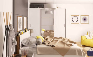 Deptford white sliding wardrobe positioned beside a modern double bed in warm lighting.
