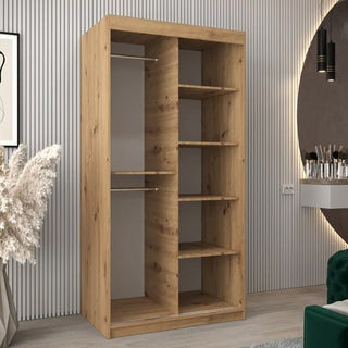 The CHOICEWARDROBE Eden 100cm Oak Mirrored Wardrobe with unique curved mirror panels and organised storage stands in a modern room with vertical wall panels, a round mirror, artwork, and pampas grass décor.