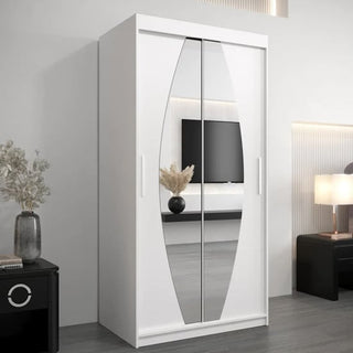 The CHOICEWARDROBE Eden 100cm White Mirrored Sliding Door Wardrobe with shelves and hanging rail stands in a modern room, reflecting a black nightstand with a lamp, dried flowers, and a wall-mounted TV in its curved mirrored panels.