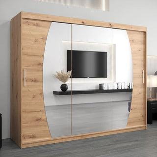 The CHOICEWARDROBE Eden 250cm Mirrored Sliding Door Wardrobe in Artisan Oak with 3 curved mirrored doors reflects a mounted TV, floating shelf, pampas grass vase, and décor in a modern room.