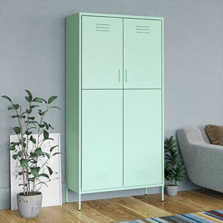 The CHOICEWARDROBE Emrik Mint Green Steel Wardrobe, a 2-door metal locker-style cabinet with adjustable shelves, stands against a gray wall, flanked by potted plants and a white-framed picture; part of a sofa appears on the right.