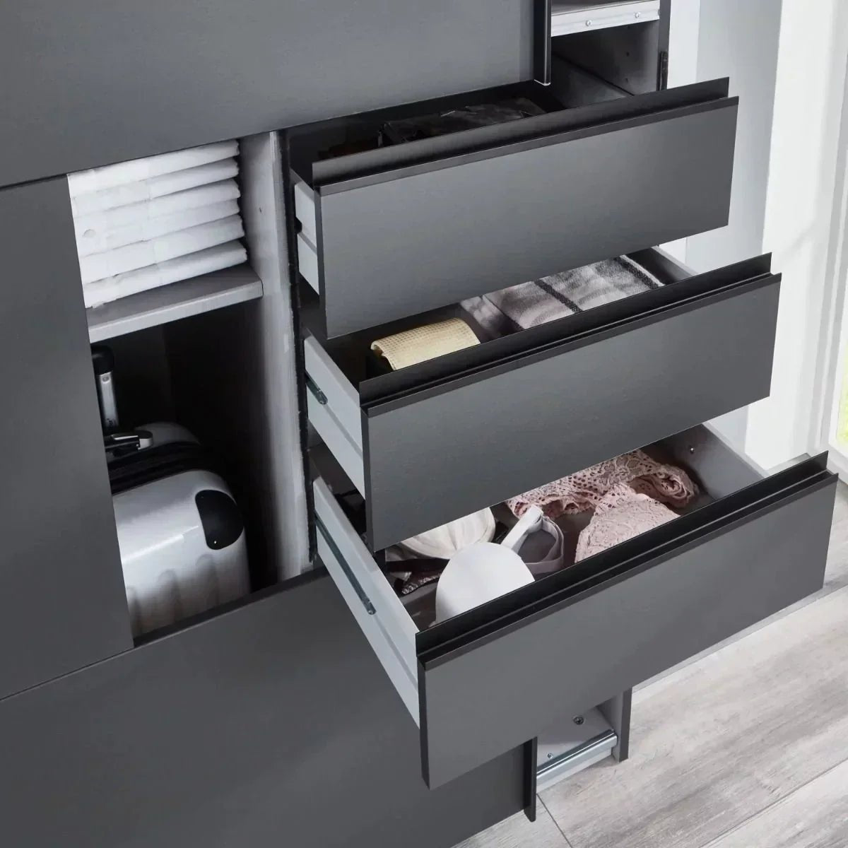CHOICEWARDROBE Ernesto sliding wardrobe in matt graphite, showing open drawers with clothes, a suitcase and stacked towels.