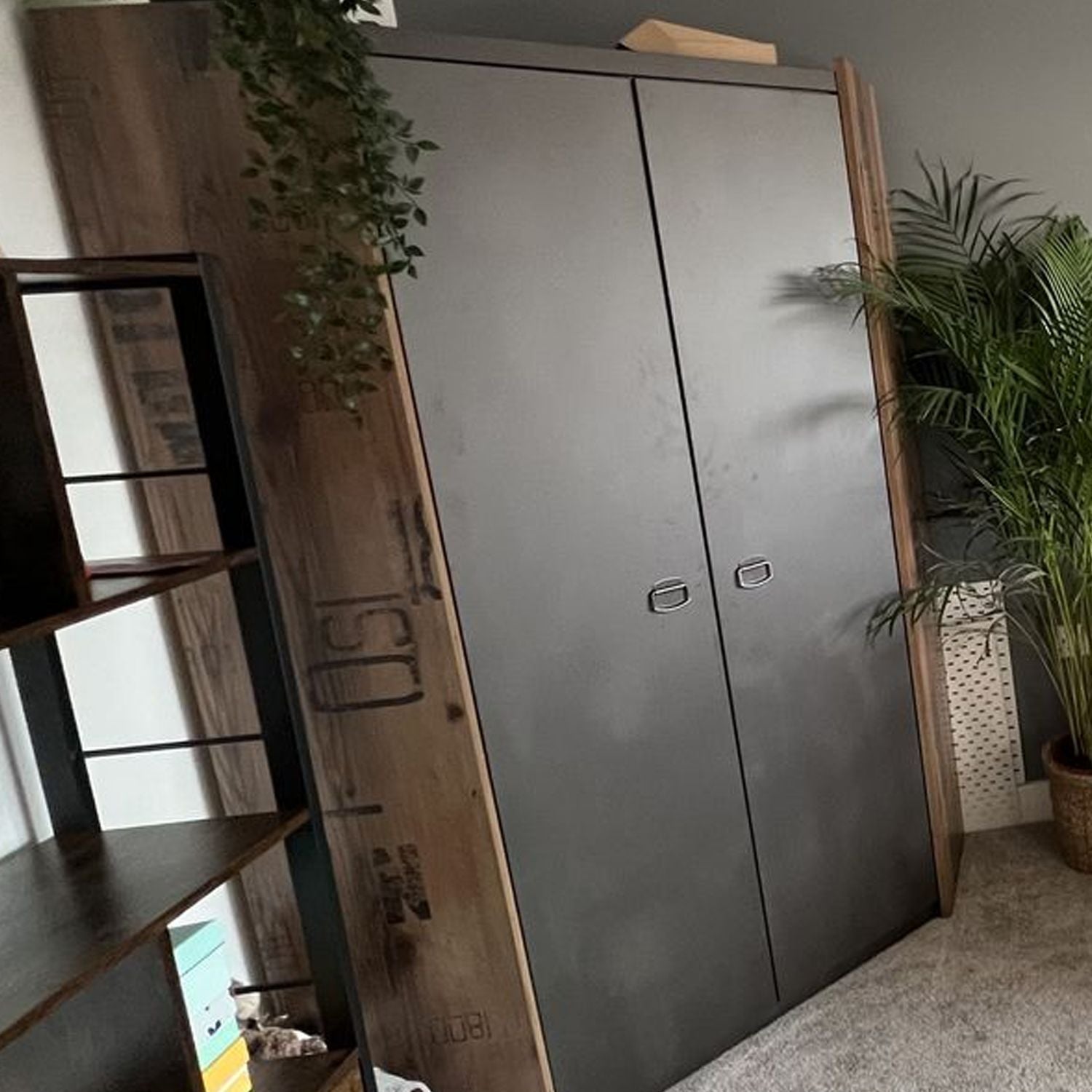 CHOICEWARDROBE L-shaped corner wardrobe in raw steel and reclaimed wood effect, beside shelving and plants.