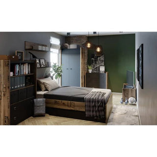 A modern bedroom with a wooden bed, gray bedding, TV, desk, shelving, green accent wall, two windows, pendant lights, a plant, decor items, and the CHOICEWARDROBE Fairbourne L-Shaped Corner Wardrobe in raw steel & reclaimed wood effect for storage.