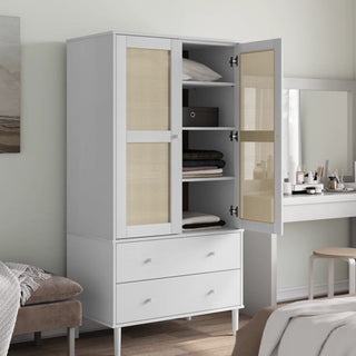 The CHOICEWARDROBE Fenland 2 Door Wooden Wardrobe in a white finish features rattan panel doors and 2 drawers, shown with open doors displaying shelves for clothes, boxes, and towels beside a vanity and stool in a stylish bedroom.
